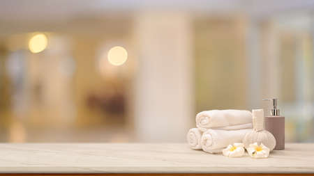 Thai spa massage concept, Massage ball, towels, bottle, frangipani flowers and copy space for montage on tabletop over blurred bright backgroundの写真素材