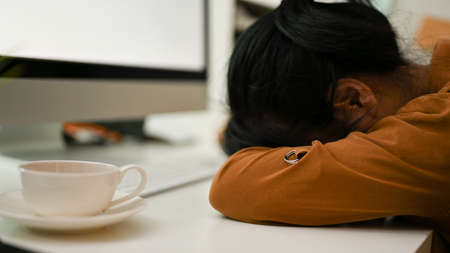 Tired female office worker laid her head down on the table, sleep on the table in the office. Lack of energy, Exhausted, Frustrated.の写真素材