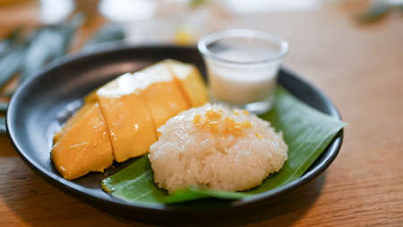 Traditional Thai sweet desserts concept, Mango with sticky rice on a black plate. Asian summer...