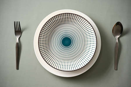 Modern dining table setting with ceramic porcelain plates and silverware on grey background. aboveの写真素材