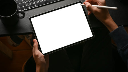 Overhead, A man using digital tablet touchpad at his modern office desk. Tablet white screen mockup.