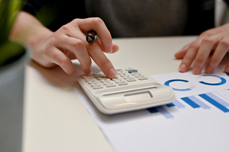 Close-up image, Female accountant working on her accounting sale report, using calculator to...
