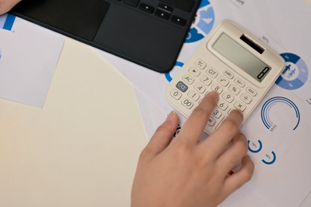 Top view, Female hand typing on calculator, using calculator or calculate her financial work with calculator at her office desk.の写真素材