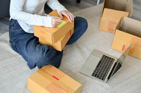 Cropped image, Female SME business entrepreneur, online shopping store owner packing the parcel...