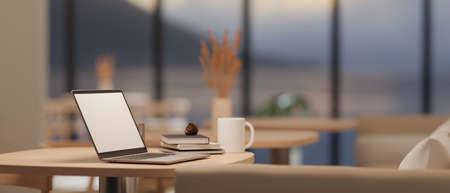 Rear view, Laptop white screen mockup, a cup of coffee and accessories on minimal wood table in...