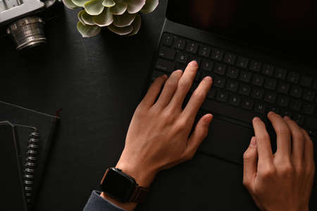 Businessman hands typing on wireless tablet keyboard in his modern black workspace. top viewの写真素材