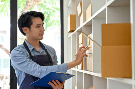 Handsome and smart Asian millennial startup businessman, online store shop owner, working in his...