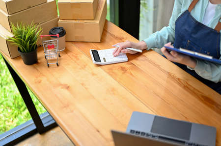Top view, Female fashion retail shop employee using calculator to calculate the price at her desk.
