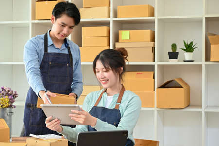 Male boss training his new staff to check product stocks on tablet in the storage room. Startup...
