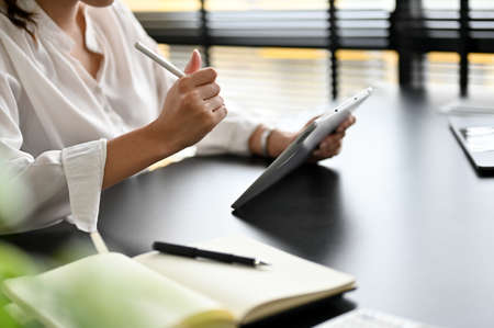 Close-up image, Female assistant or secretary working at her office desk workspace, using tablet touchpad, checking her boss schedule.の写真素材