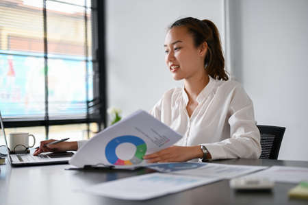 Beautiful Asian millennial female financial consultant planning a business financial investment plan and strategy in the office.の写真素材