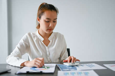 Female financial manager reviewing a business financial investment turnover report in the office. Business woman working with report.の写真素材