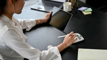 Close-up image, Female accountant using digital tablet and calculator to calculate her business...