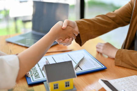 House insurance broker or real estate agent shaking hand with the new owner in the office....