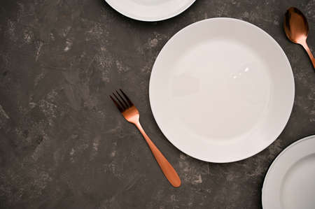 Modern dining table setting background with empty white plate and luxury silverware fork and spoon...