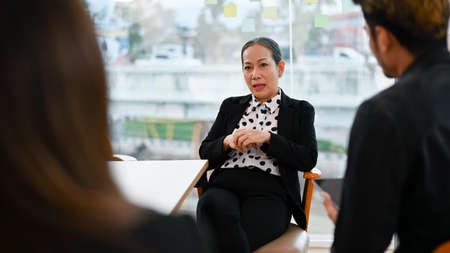 Professional Asian aged businesswoman or female boss mentoring, coaching or complaining problems to...