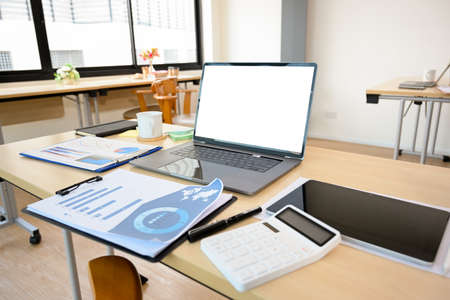 Modern office desk with open laptop computer white screen mockup, financial and marketing report,...