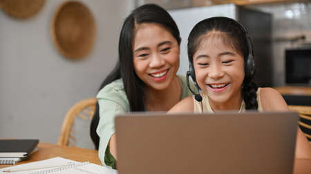 Pretty cute Asian girl enjoy watching funny video or learning an online class via laptop computer...