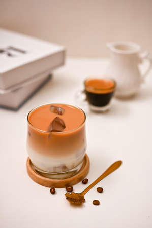 A glass of iced coffee with cream milk. Iced caramel latte, iced latte on a white table background. Coffee shop and cafe drinks menuの写真素材