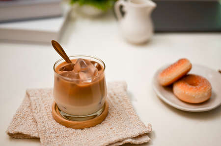 A modern office workspace with an iced latte and a plate with tasty sweet donuts. close-up image