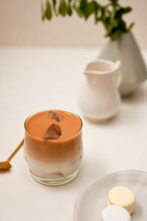 Iced latte coffee, a glass of coffee with milk on a minimal white table background. Iced caramel latteの写真素材