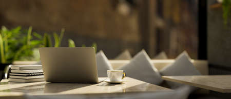 Laptop computer and accessories on a modern marble table over the luxury and comfortable restaurant...