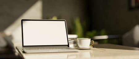 Modern portable notebook laptop computer blank screen mockup and a cup of coffee on white marble...