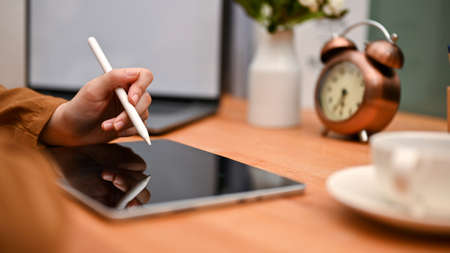 Cropped, close-up image, Female hand using a stylus pen with a digital tablet touchpad at her...
