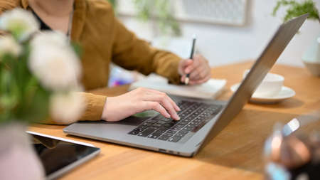 Cropped image, Female college student doing her homework and searching the information on the...