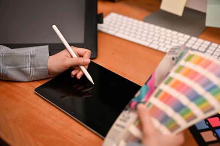 Professional female interior designer or graphic designer working on her project, using portable...