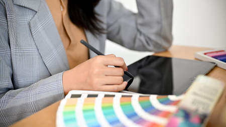 Female graphic designer or interior designer working at her office desk and using digital tablet....