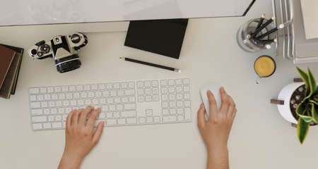 Overhead shot, A female hands typing on computer keyboard on a modern office workspace with camera,...