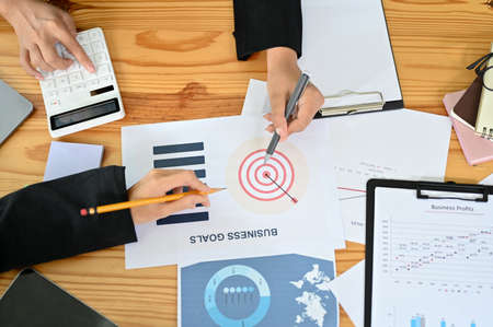 Overhead shot of a business meeting table with businesspeople's hands working on the business report...