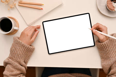 Top view, A female freelance blogger sits in her minimal worktable using digital tablet touchpad,...