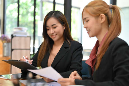 Attractive asian businesswoman working and planning the project with female colleague in the office workplace.の写真素材