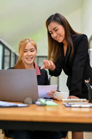 Portrait of a cheerful and friendly asian female boss training and teaching her new female assistant in the office.の写真素材