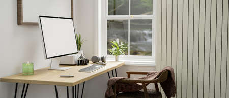 Minimal white home workplace with computer and accessories on wood table against the white wall near...