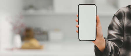 A female in Scott shirt holding showing a smartphone white screen mockup over blurred modern...