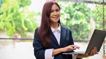 Charming and smart asian businesswoman standing in front of the meeting and using laptop computer....