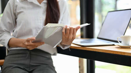 Cropped, close-up image, A businesswoman reading a business report, researching some informations on...