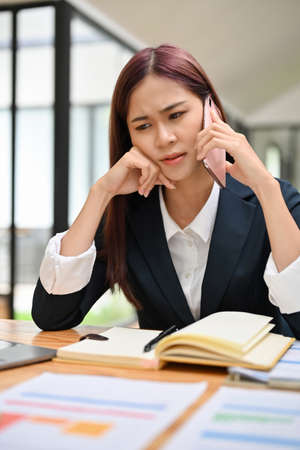 Businesswoman talking on the phone with a serious face expression. Arguing on the phone call. Unhappy, Dissatisfied, Stressed phone call.の写真素材