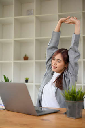 Portrait of a beautiful young Asian businesswoman stretching her arms and relaxing at work after a long day. Office syndrome conceptの写真素材