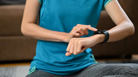 Female checking her heart rate and pulse on her modern smartwatch after workout at home. cropped imageの写真素材