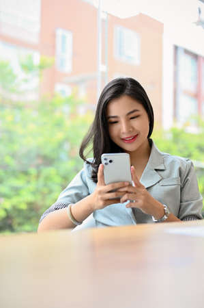 Portrait of a beautiful millennial asian businesswoman or female manager using a smartphone while she was in the meeting.の写真素材
