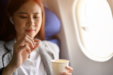 Young Asian female passenger feeling dizzy, taking an airsick motion sickness pills before take off...