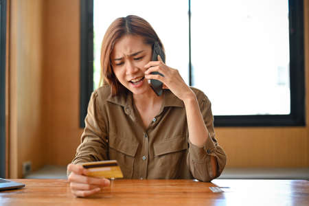 Angry and furious young Asian woman calling credit card call-centre service to complain about her...