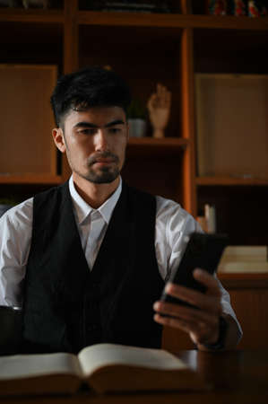 Portrait of a professional Asian businessman or male entrepreneur at his office desk using a...