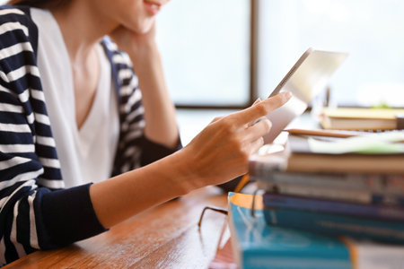 Cropped image, A beautiful young asian female college student using a portable digital tablet for...