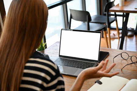A millennial female college student remote working in the coffee shop, using a portable laptop...