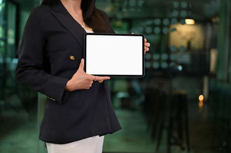 Successful businesswoman in formal suit holding a blank screen of portable tablet touchpad. cropped...
